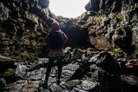 女旅行者探索冰原的熔岩隧道图片