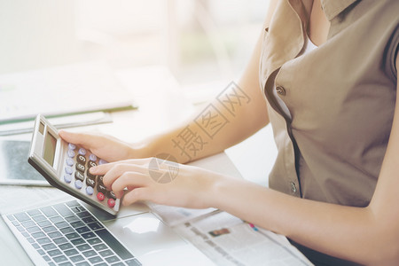 商业妇女使用计算器笔记本电脑和报纸在办公桌工作图片