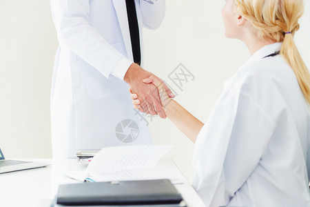 医院生向另一名显示成功和专业保健工作人员团队合的医生握手图片