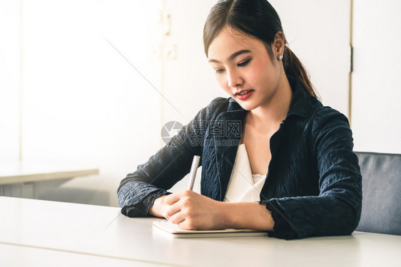 美丽的年轻女士坐在办公桌旁笔记本上写信件内容作和秘书职务概念图片