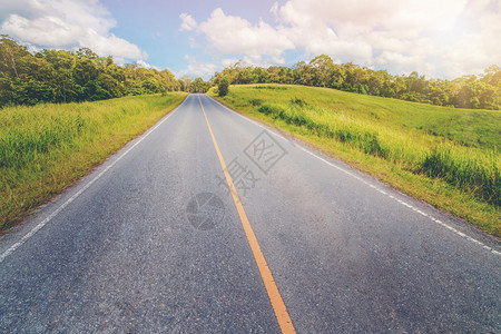 夏日蓝天白云下穿过绿草地的高速公路图片