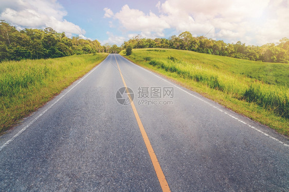 夏日蓝天白云下穿过绿草地的高速公路图片