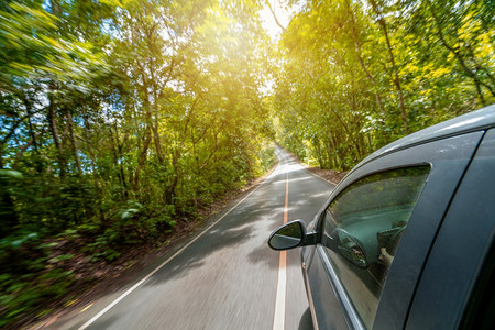 夏季在森林高速公路上旅行的黑色汽车图片