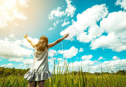 年轻美女向阳光晴朗的蓝天伸出双臂图片