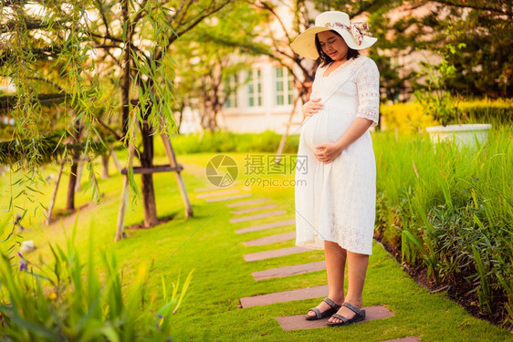 年轻孕妇在花园看着肚子图片