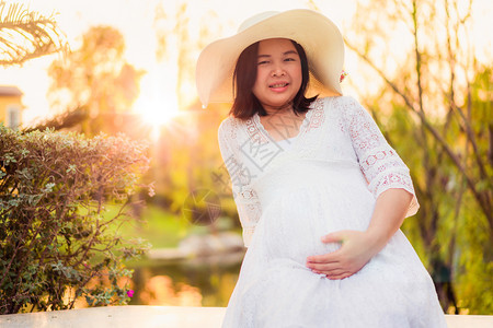 年轻孕妇在花园里扶着肚子图片