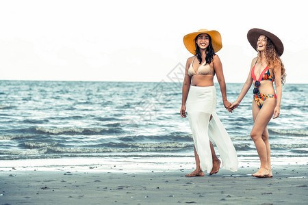 比基尼的快乐妇女一起在暑假的热带沙滩上晒太阳图片
