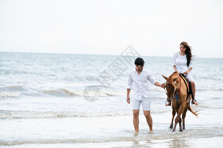 年轻夫妇在热带海滩骑马图片