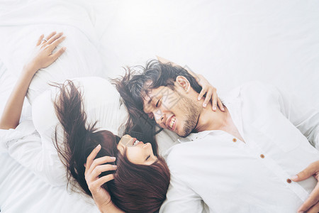 快乐的年轻夫妇在早晨醒来后家庭卧室放松图片