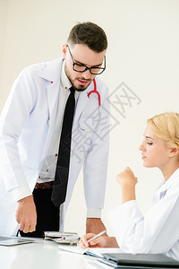 女医生与坐在桌边的另一个男医生交谈图片