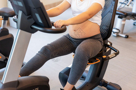 孕妇在健身房骑动感单车图片素材