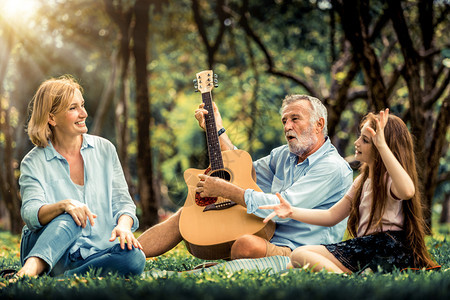 快乐的家庭夏天弹吉他坐在公园里一起唱歌图片