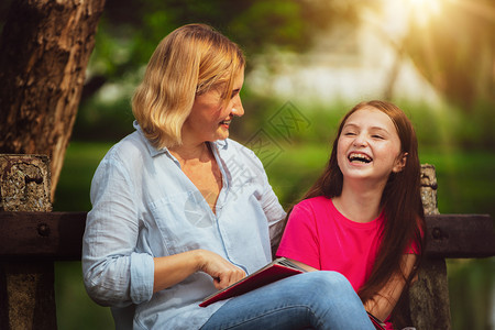 户外公园中母亲和孩子在草地上看书阅读图片