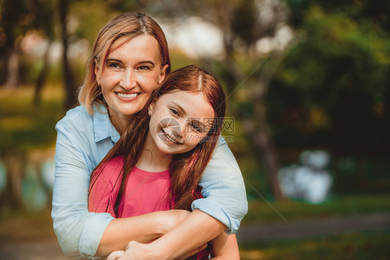 户外公园中母亲从背后拥抱女儿图片
