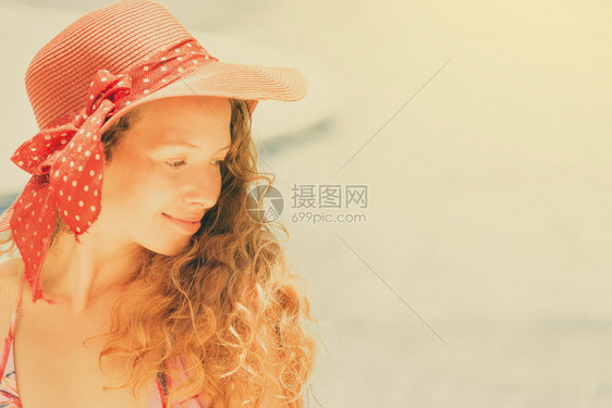 穿着泳衣的快乐年轻女子戴着帽子在豪华度假村游泳池玩图片