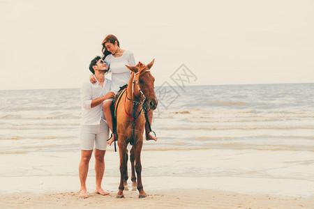 暑假年轻夫妇在热带海滩骑马度蜜月图片