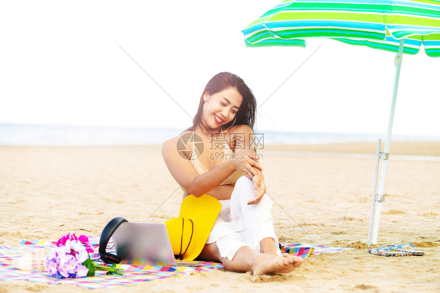 夏天坐在热带沙滩上快乐的年轻女子图片