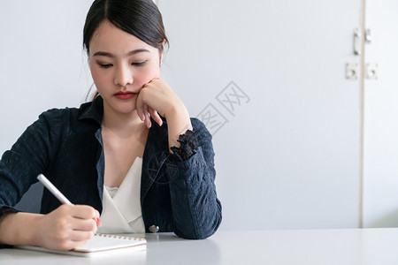 美丽的年轻女士坐在办公桌旁写信件图片