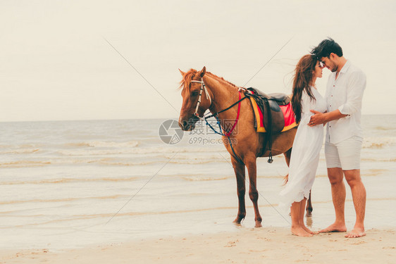 年轻夫妇在海滩骑马度蜜月图片