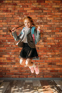 可爱的女学生背着包在校园里跳图片