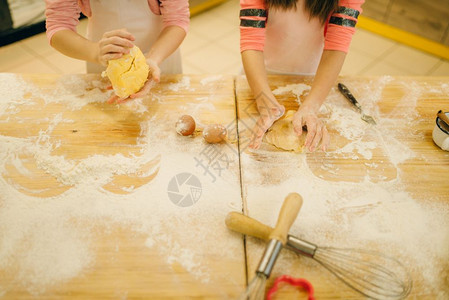 两个小女孩厨师揉面团在厨房准备做饼干图片