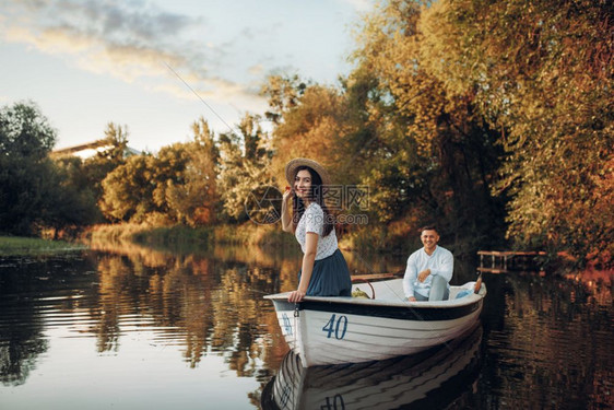 夏日宁静的湖边漂亮女士和男人沿着河划船浪漫约会图片
