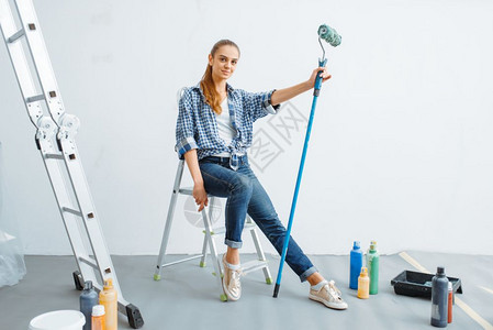 女油漆工拿着滚筒坐在梯子上图片
