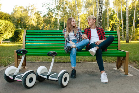 在公园的长椅上坐着带平衡车的年轻夫妇图片