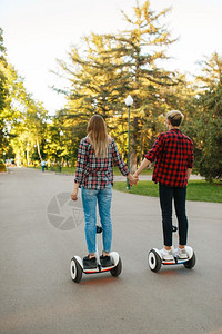 在公园手牵手使用平衡车的年轻夫妇图片