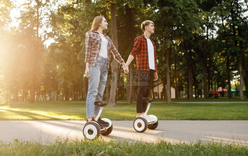 在公园手牵手使用平衡车的年轻夫妇图片