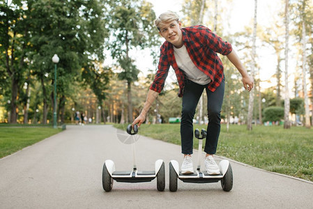 青年男子在公园使用平衡车并手扶平衡车图片