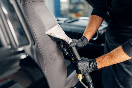 戴手套的男洗车工对汽车内部进行化学清洗除尘图片