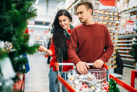 在超市购买圣诞树装饰品的夫妇背景图片