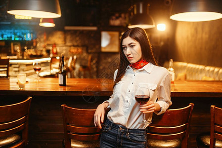 有吸引力的年轻女子在木酒吧柜台喝红女顾客在吧闲暇图片