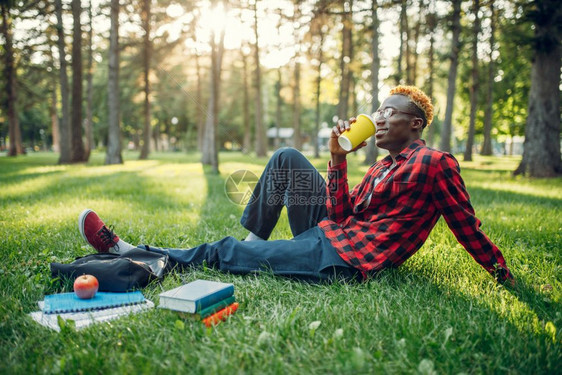 黑人学生在公园的草地上喝咖啡图片