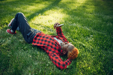 黑人青年躺在草地上看手机图片