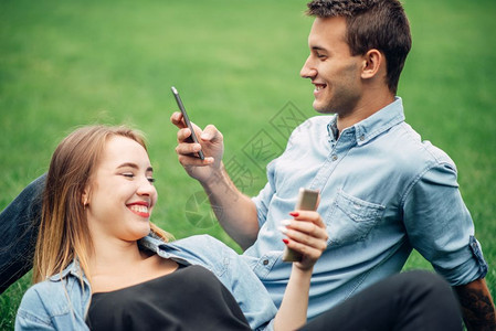 夫妻躺在草地上使用智能手机图片