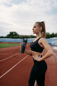 女运动员在体育场穿着运动服喝水图片