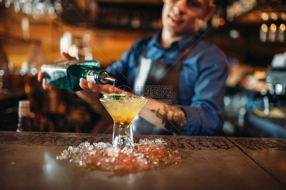 酒吧招待将饮料倒入满冰的黑玻璃杯中图片