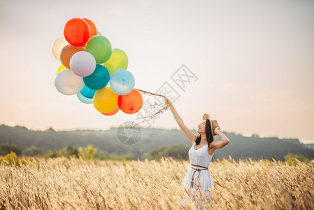 麦田漂亮女人抓着彩色气球图片