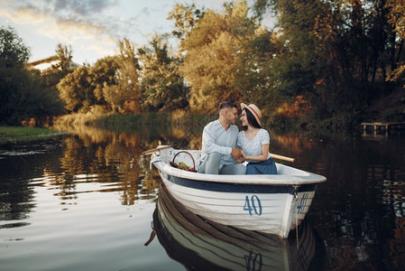 浪漫的约会划船旅行男人和女沿河行驶爱夫妻和水果篮子在船上放松图片