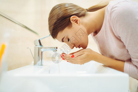 女人在浴室的水槽里洗脸图片