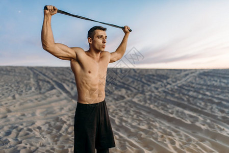 沙漠上男运动员拉着绳子举过头顶图片