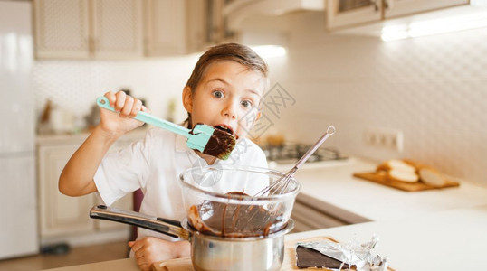 小孩在厨房做饭快乐的孩子准备甜点小孩在碗里吃巧克力图片