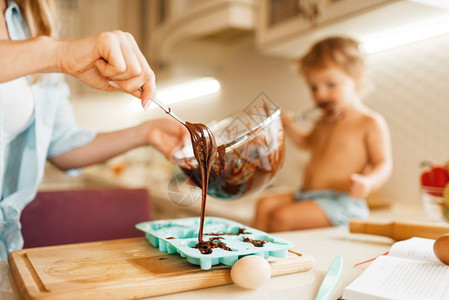 年轻妈妈和孩子准备融化巧克力做糕点图片