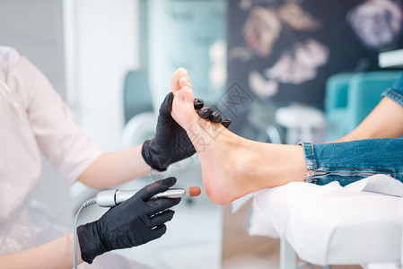 戴着黑色手套的医生对顾客的脚做治疗图片