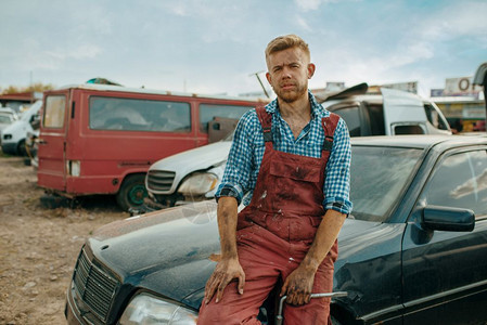 废弃汽车垃圾场里的一名男修车工图片