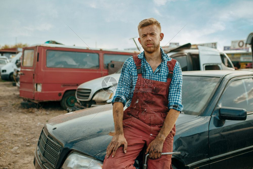 废弃汽车垃圾场里的一名男修车工图片