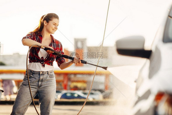 夏天年轻妇女用自助高压水清洗车辆图片