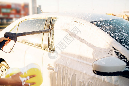 夏天年轻妇女用自助高压水在户外清洗车辆上的泡沫高清图片